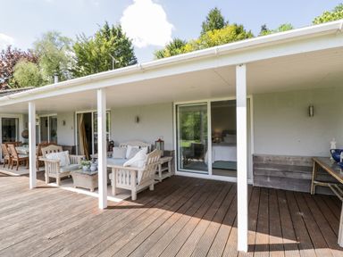 A covered wooden deck with outdoor seating and a dining table at The River House Avon Valley Stonehenge with fishing Salisbury