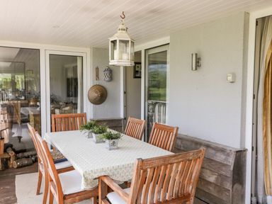 An outdoor dining area with a table covered with a cloth and wooden chairs at The River House Avon Valley Stonehenge with fishing Salisbury