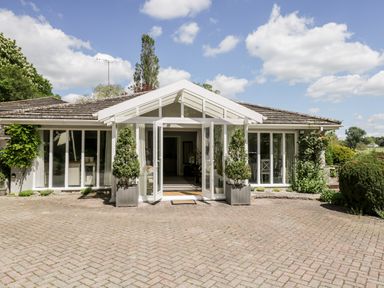 Front of a single story house with large glass doors and windows with plants in pots at The River House Avon Valley Stonehenge with fishing Salisbury