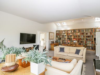 A living room with sofas a wall-mounted TV and bookshelves at The River House Avon Valley Stonehenge with fishing Salisbury