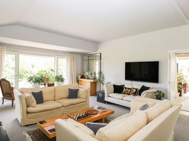 A living room with sofas a wooden coffee table with a chessboard a wall mounted tv and plants at The River House Avon Valley Stonehenge with fishing Salisbury