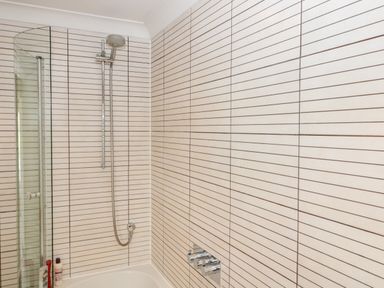 A bathroom with a shower head above a bathtub and a glass partition at The River House Avon Valley Stonehenge with fishing Salisbury