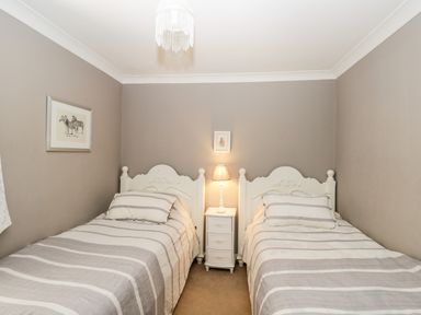 A bedroom with two single beds and a small bedside table with a lamp at The River House Avon Valley Stonehenge with fishing Salisbury
