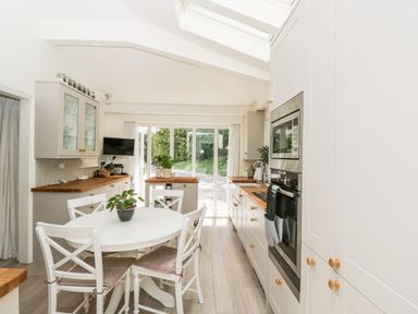 A kitchen with a round dining table and white chairs next to cabinets and an oven at The River House Avon Valley Stonehenge with fishing Salisbury