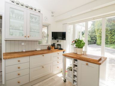 A kitchen with wooden countertops glass cabinet and potted plants on a movable island at The River House Avon Valley Stonehenge with fishing Salisbury