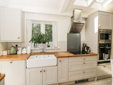A kitchen with wooden countertops plants on the windowsill and built in oven at The River House Avon Valley Stonehenge with fishing Salisbury