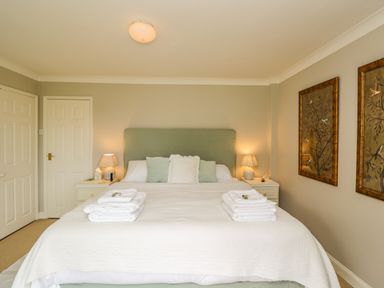 A bedroom with a bed with white linens and pillows two bedside tables with lamps and folded towels on the bed at The River House Avon Valley Stonehenge with fishing Salisbury
