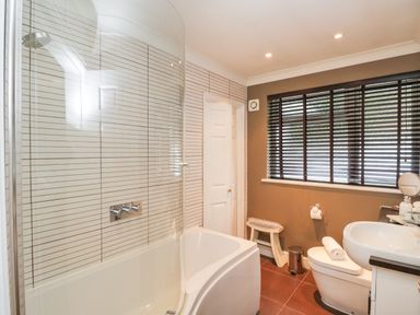 A bathroom with bathtub shower white sink toilet brown floor and window blinds at The River House Avon Valley Stonehenge with fishing Salisbury