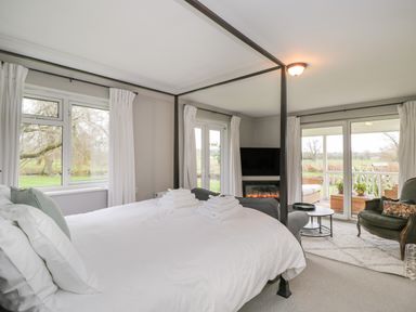 A bedroom with a four-poster bed towels on bed a fireplace and seating area at The River House Avon Valley Stonehenge with fishing Salisbury