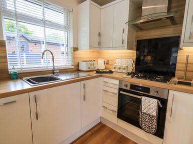 A kitchen with a sink stove oven toaster kettle and cabinets at Black Dog Lodge Thirlmere 3 White Cross Bay near Windermere