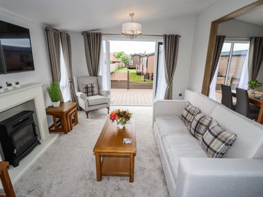 A living room with a sofa armchair coffee table fireplace and sliding glass doors at Bramblewick in Runswick Bay near Staithes