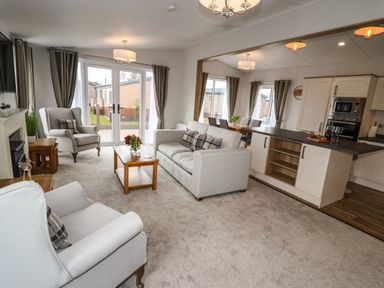 A living room with chairs sofa coffee table and open kitchen at Bramblewick in Runswick Bay near Staithes