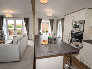 An open kitchen and living room area with a kitchen island with wine and glasses at Bramblewick in Runswick Bay near Staithes