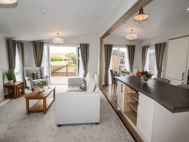 A living room with sofa armchair coffee table and plants next to an open kitchen and dining area at Bramblewick in Runswick Bay near Staithes