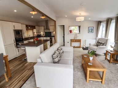 An open living room and kitchen with a sofa armchair coffee table and kitchen island at Bramblewick in Runswick Bay near Staithes