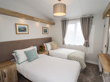 A bedroom with two single beds a window with curtains and two framed pictures on the wall at Bramblewick in Runswick Bay near Staithes