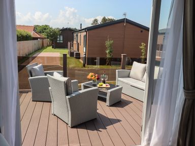 An outdoor patio with wicker chairs and a table with drinks and flowers at Bramblewick in Runswick Bay near Staithes