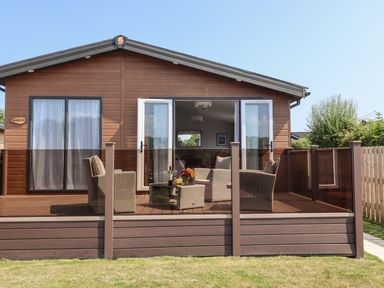 A wooden cabin with a porch and outdoor furniture on a grassy lawn at Bramblewick in Runswick Bay near Staithes