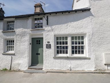 The exterior of a white stucco building with a green door and multiple windows at Old Toffee Shop Ambleside