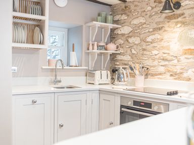 A kitchen with white cabinets a stone wall a toaster an electric kettle and utensils at Old Toffee Shop in Ambleside