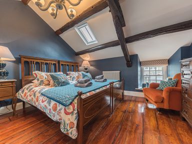 A bedroom with a wooden bed and colorful bedding under exposed ceiling beams at Old Toffee Shop in Ambleside