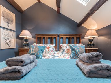 A bedroom with a bed with blue quilt and animal print cushions with bedside tables and lamps at Old Toffee Shop Ambleside