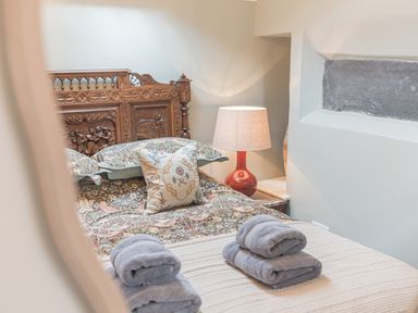 A bedroom with a carved wooden headboard patterned bedspread and folded towels on the bed at Old Toffee Shop in Ambleside