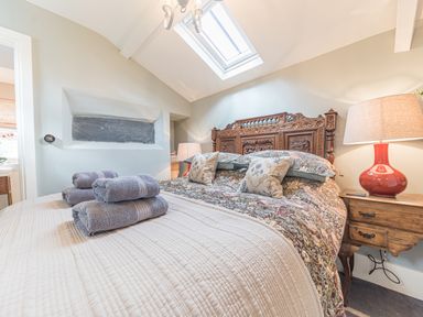 A bedroom with a carved wooden bed frame floral bedding bedside tables with lamps and folded towels on the bed at Old Toffee Shop in Ambleside