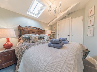 A bedroom with an ornate wooden headboard two bedside tables with lamps and folded towels on the bed at Old Toffee Shop Ambleside