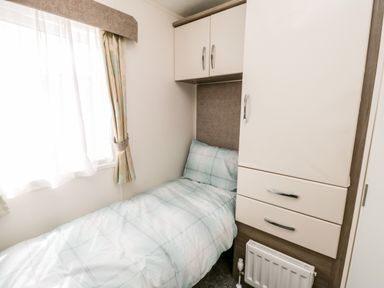 A small bedroom with a single bed next to a window and built-in wardrobe at The Rodley Pines in Cayton