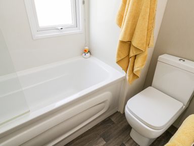 A bathroom with a bathtub a toilet yellow towels and a rubber duck at The Rodley Pines in Cayton