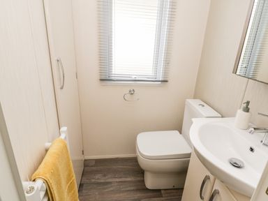 A bathroom with a toilet sink towel rack and window blinds at The Rodley Pines in Cayton