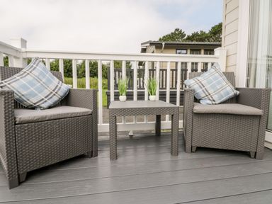 A porch with two wicker armchairs with cushions and a small table with plants at The Rodley Pines in Cayton