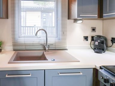 A kitchen sink with a faucet below a window and a coffee machine on the counter at The Rodley Pines in Cayton