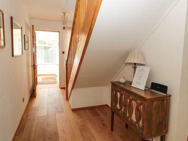 A hallway with wooden flooring a small wooden cabinet lamp and a few framed pictures at Rose Bank in Belford