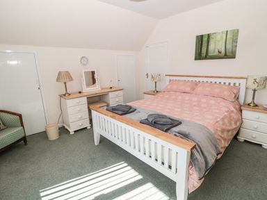 A bedroom with a double bed with pink bedding and two folded towels on the bed at Rose Bank in Belford