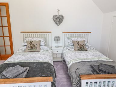 A bedroom with two single beds side by side with a nightstand and lamp in between at Rose Bank in Belford