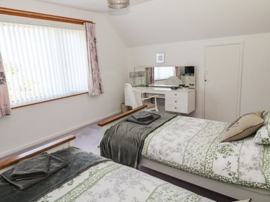 A bedroom with two single beds a window with blinds and curtains and a desk with a chair at Rose Bank in Belford