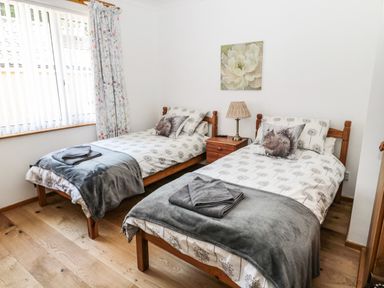 A bedroom with two single beds a bedside table with a lamp and towels on the beds at Rose Bank in Belford