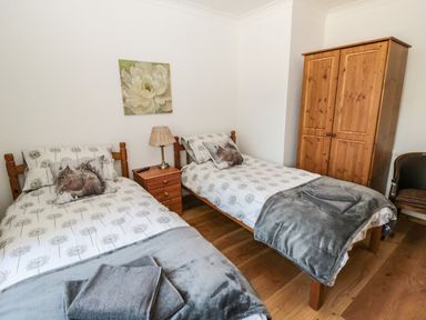 A bedroom with two single beds and a wooden wardrobe at Rose Bank in Belford