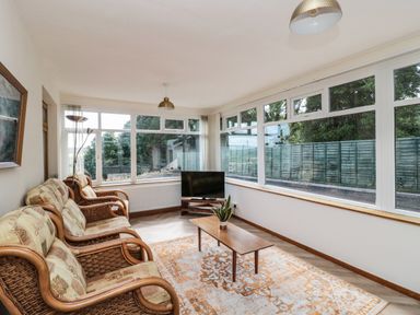 A sitting room with wicker armchairs a wooden coffee table and a television at Rose Bank in Belford