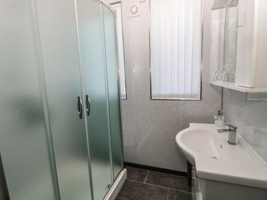 A bathroom with a frosted glass shower enclosure a white sink with a faucet and a window with vertical blinds at Rose Bank in Belford