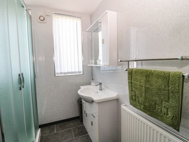 A bathroom with a sink, a mirror cabinet, a shower enclosure, and a green towel on a rail at Rose Bank in Belford