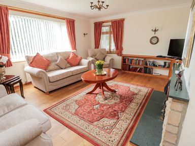 A living room with sofas a wooden coffee table and a bookcase at Rose Bank in Belford