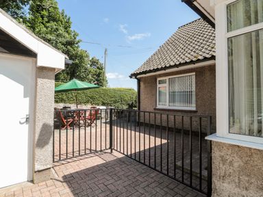 An outdoor patio area with a table and chairs under a green umbrella and a black metal gate at Rose Bank in Belford