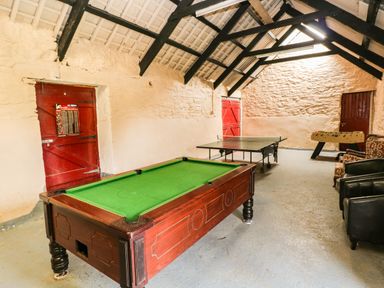 A game room with a pool table ping pong table foosball table and chairs at Trewrach Cottage in Dinas Cross