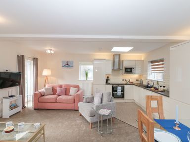 An open plan living room and kitchen with sofas a dining table and kitchen appliances at Weydale Avenue in Scarborough
