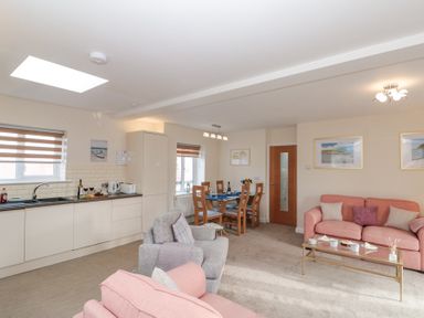 An open plan living room and kitchen with pink sofas a gray armchair a glass coffee table and a dining table with chairs at Weydale Avenue Scarborough