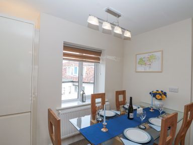 A dining room with a glass table set with plates glasses and candles next to a window with a wooden blind at Weydale Avenue in Scarborough