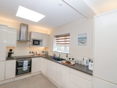 A kitchen with white cabinets black countertop built in oven microwave and various kitchen items at Weydale Avenue in Scarborough